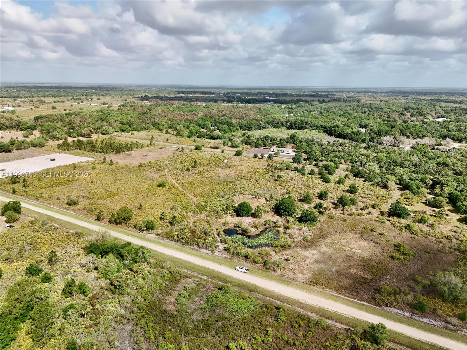 An aerial view shows a dirt road, a small pond, and a house in a field — 17923 NW 250TH, Okeechobee FL 34972, OKEECHOBEE, FL