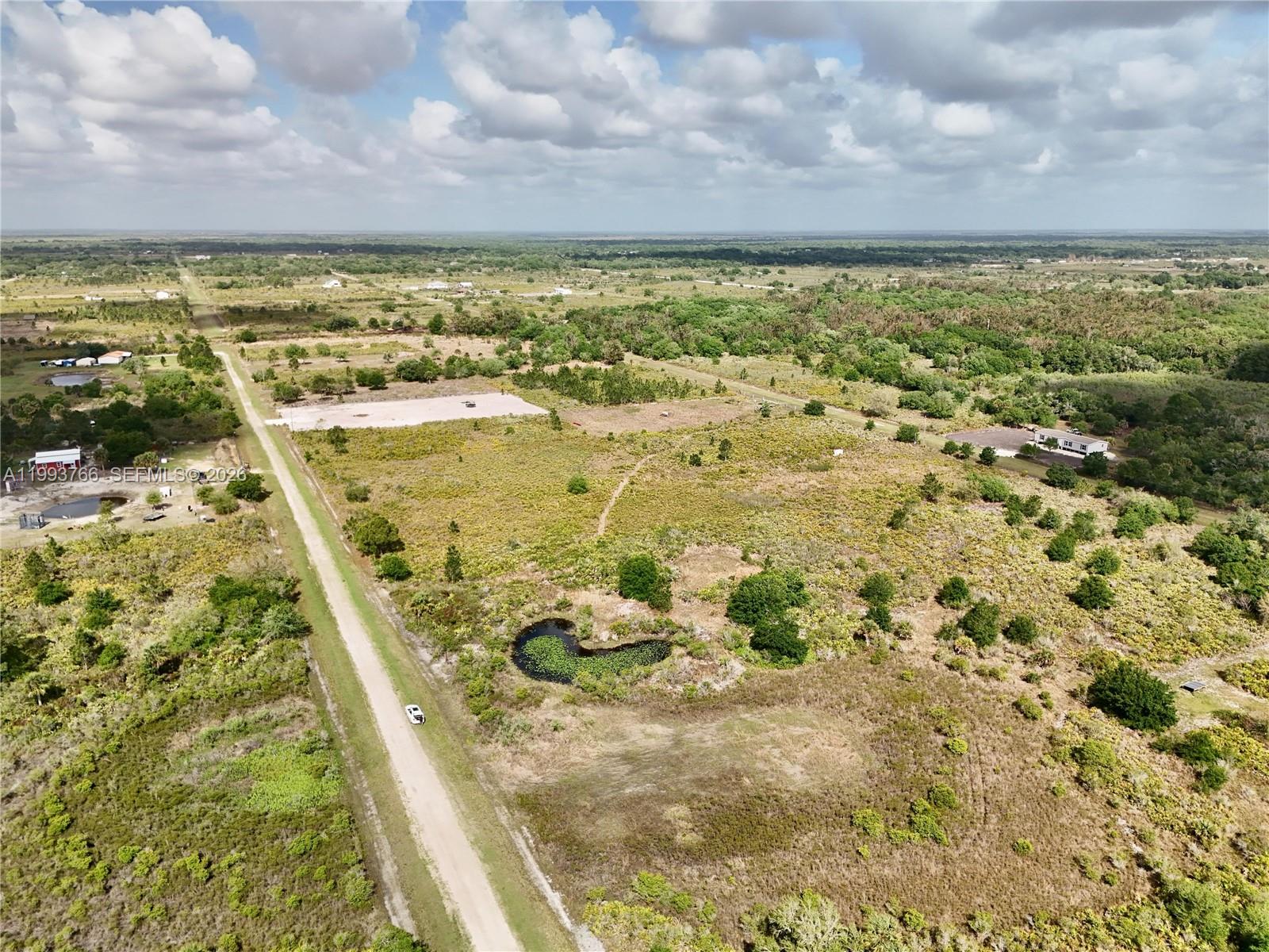 An aerial view shows a dirt road running through a large, grassy, rural plot — 17923 NW 250TH, Okeechobee FL 34972, OKEECHOBEE, FL