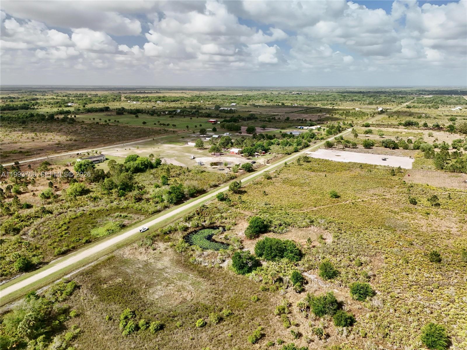 An aerial view shows a rural landscape with a road, a small pond, and scattered buildings — 17923 NW 250TH, Okeechobee FL 34972, OKEECHOBEE, FL