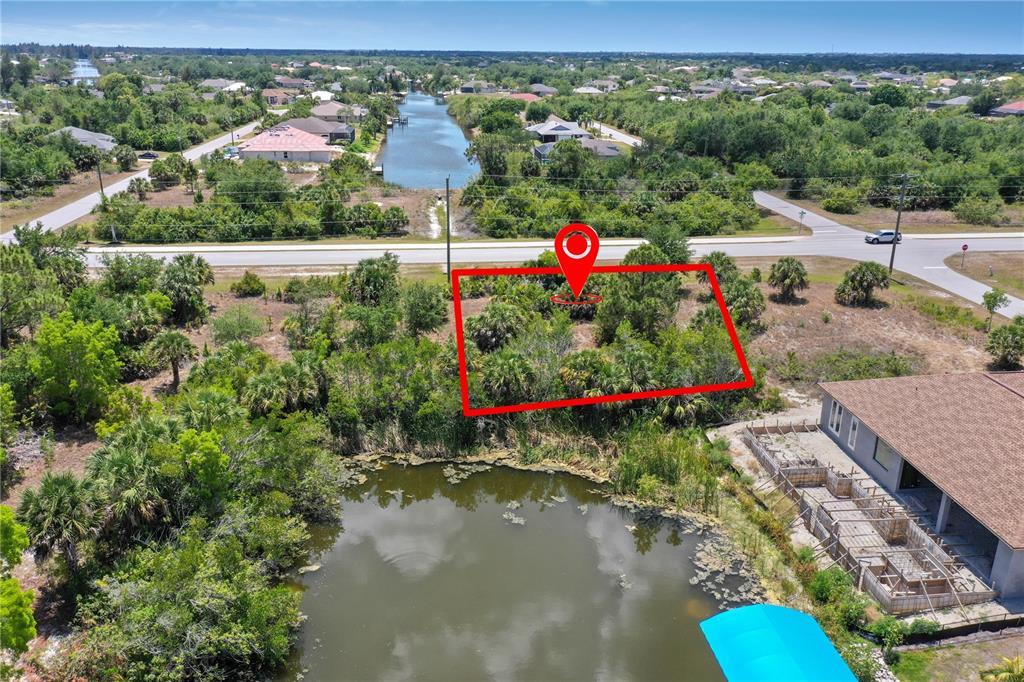An aerial view shows a vacant, rectangular lot bordered by a road and a pond — 14530 INGRAHAM BOULEVARD, PORT CHARLOTTE, FL