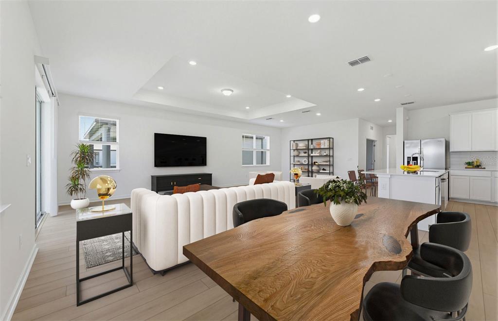An open-concept living and dining area features a live-edge wood table and white sofa — 33383 HERDS HALLOW WAY, WESLEY CHAPEL, FL