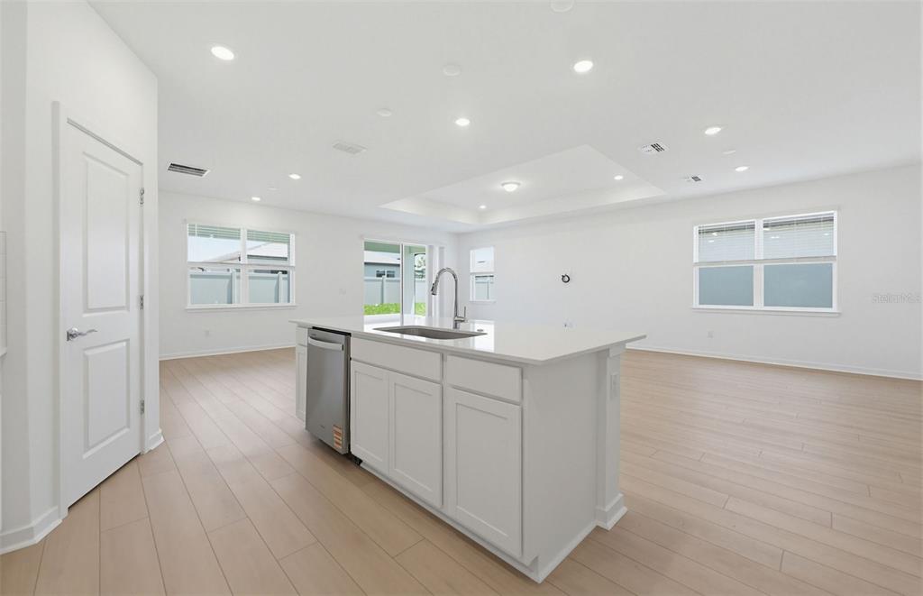 A kitchen island with a stainless steel dishwasher and sink sits in a white room — 33383 HERDS HALLOW WAY, WESLEY CHAPEL, FL