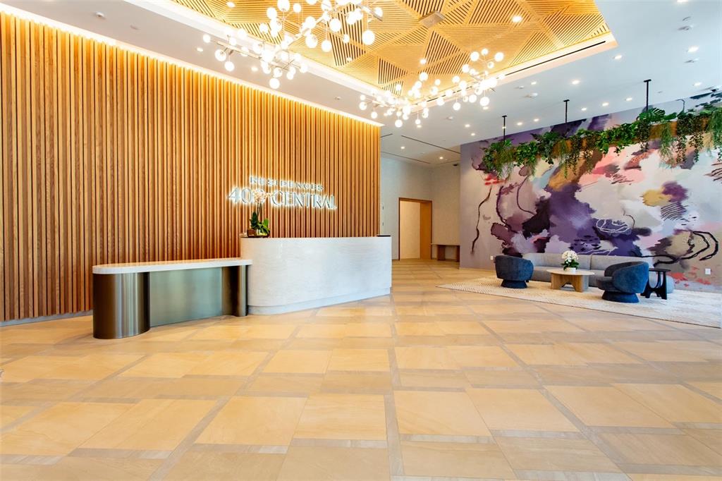 A modern lobby features a white reception desk, wood-slat wall, and a large abstract mural — 400 CENTRAL AVENUE UNIT 2601, ST PETERSBURG, FL