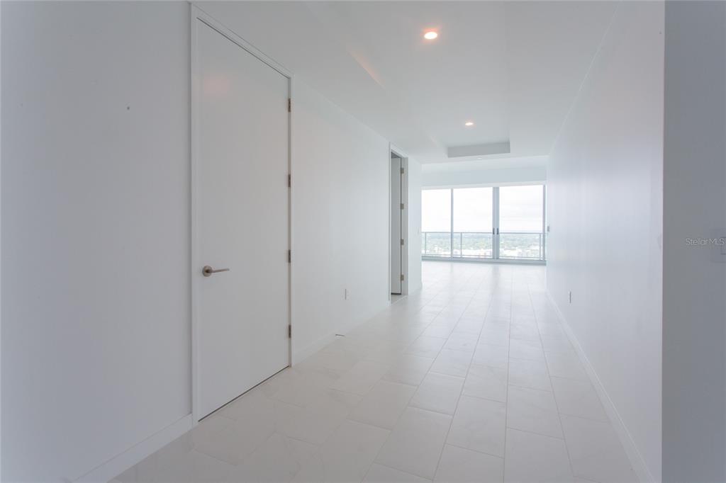 A bright hallway with white walls, tile flooring, and a view of windows at the end — 400 CENTRAL AVENUE UNIT 2601, ST PETERSBURG, FL