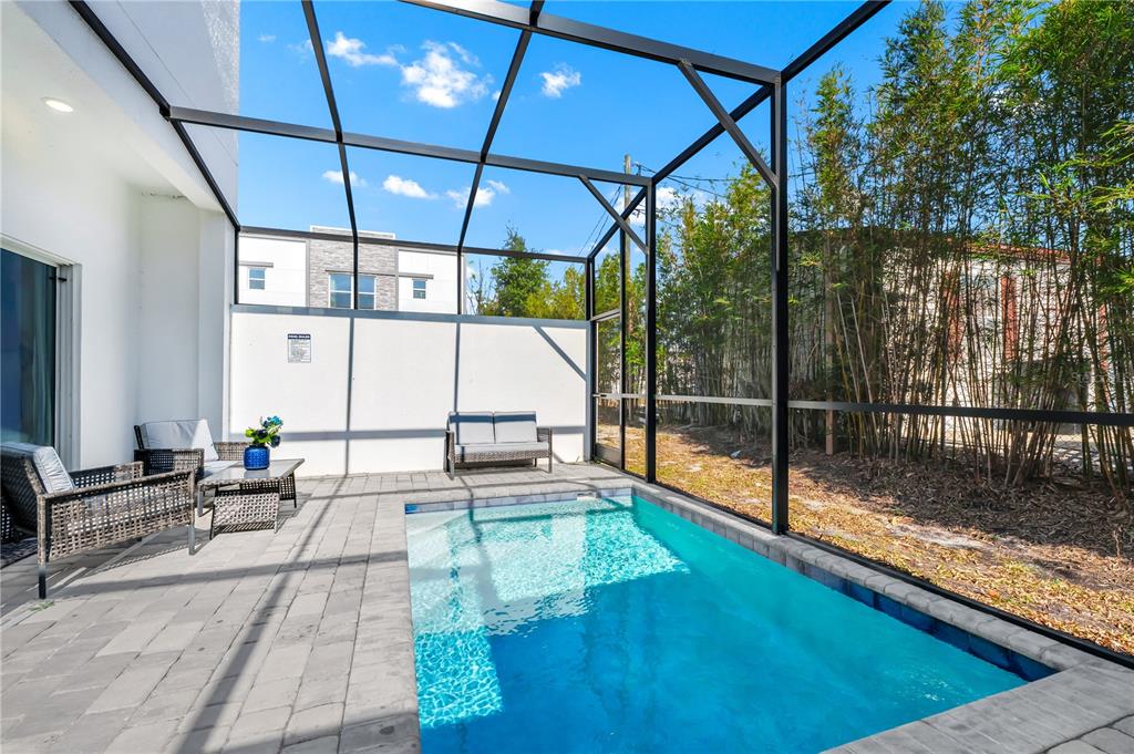 A screened-in patio features a small rectangular swimming pool and outdoor wicker furniture — 240 FAMAGUSTA DRIVE, DAVENPORT, FL
