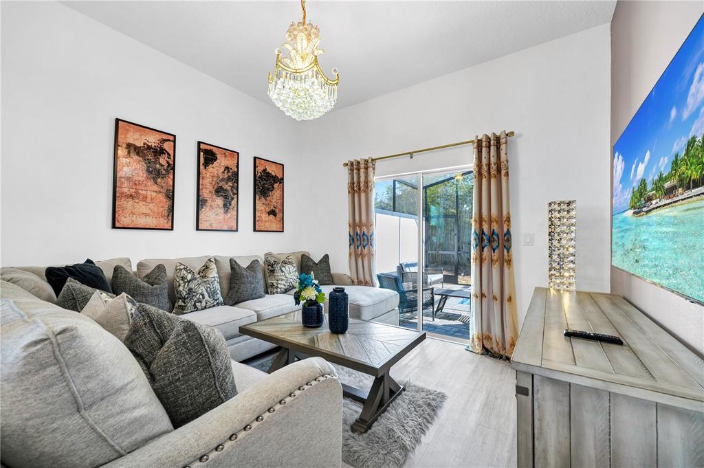A living room features a sectional sofa, a coffee table, a chandelier, and a television — 240 FAMAGUSTA DRIVE, DAVENPORT, FL
