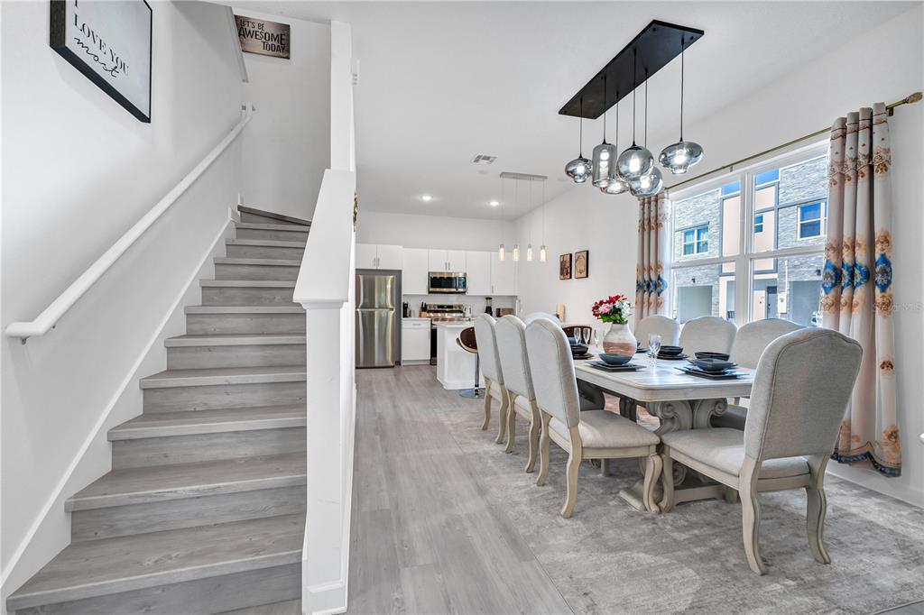 A dining area with a long table and chairs sits next to a modern kitchen — 240 FAMAGUSTA DRIVE, DAVENPORT, FL