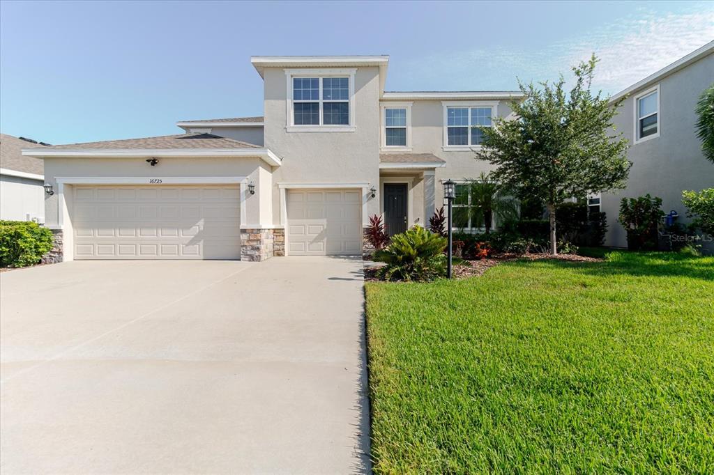 A two-story suburban house features a three-car garage, stucco exterior, and a front lawn — 16725 BARNWOOD PLACE, BRADENTON, FL