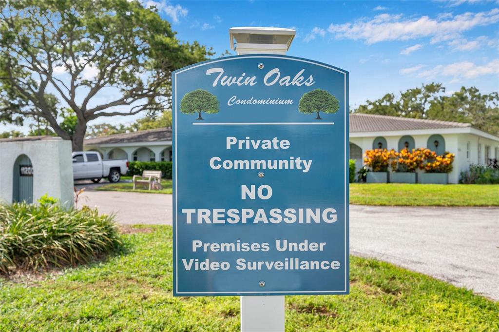 A blue sign for Twin Oaks Condominium stands in front of a residential building — 11200 102ND AVENUE UNIT 115, SEMINOLE, FL