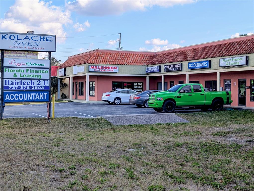 A strip mall building with a parking lot and a large sign in the foreground — 7414 STATE ROAD 52, PORT RICHEY, FL