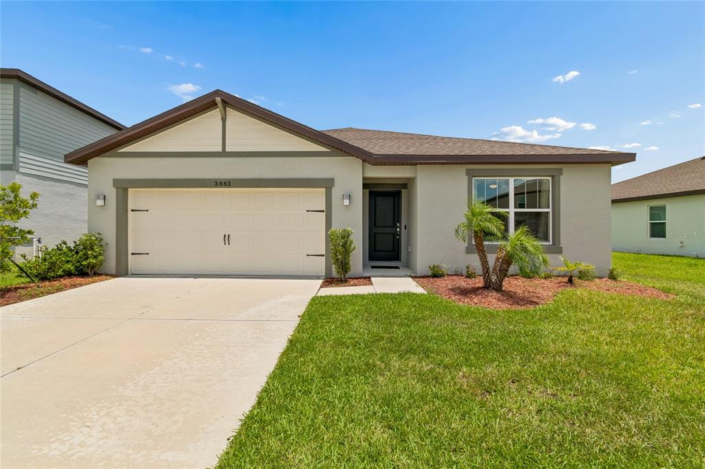 A single-story house with a beige stucco exterior, a two-car garage, and a front lawn — 3883 CAPRI COAST DRIVE, PLANT CITY, FL
