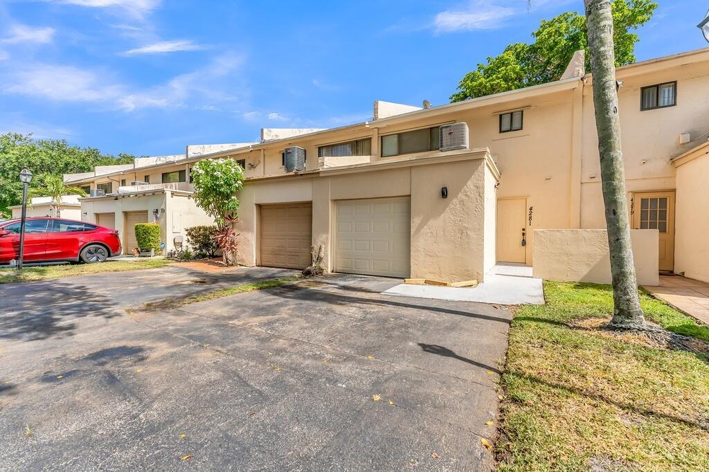 A beige townhouse exterior features a paved driveway, two garage doors, and a front entrance — 4281 NW 76th Avenue, Davie FL 33328, DAVIE, FL