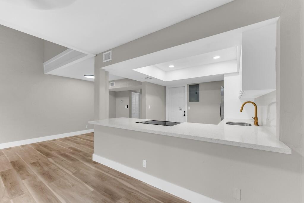 A kitchen with white countertops and a gold faucet overlooks a living area with flooring — 4281 NW 76th Avenue, Davie FL 33328, DAVIE, FL