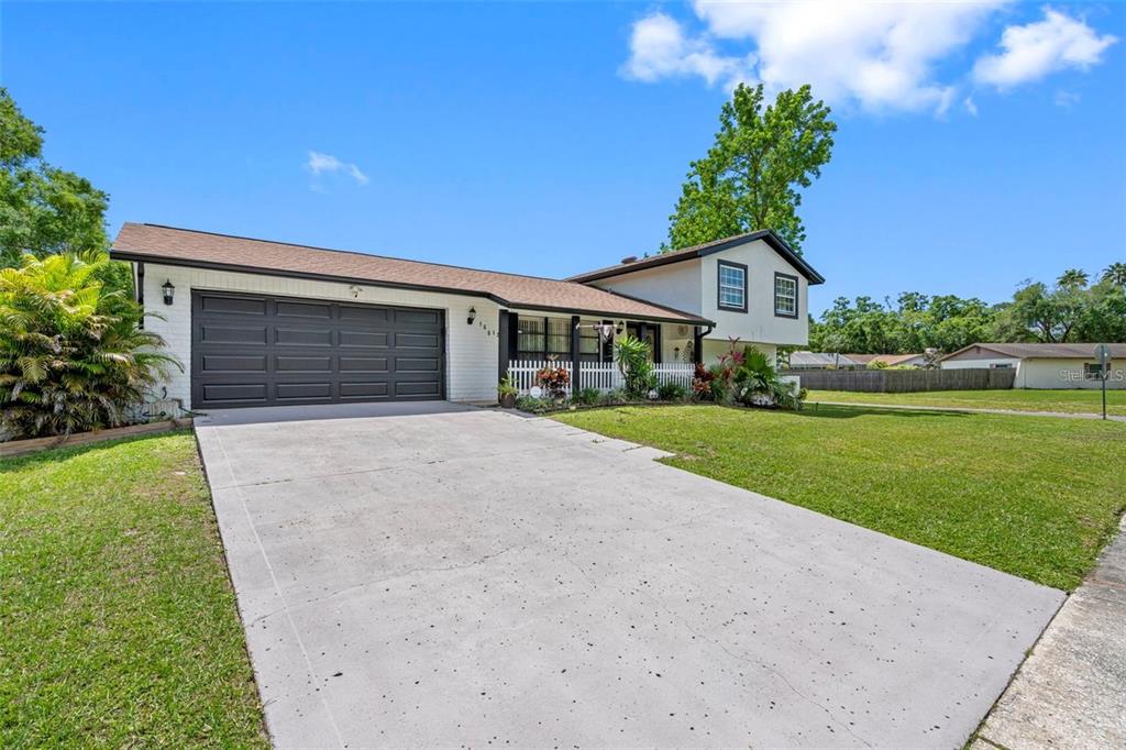 A two-story house with a white brick exterior, a dark garage door, and a concrete driveway — 16513 SILVERHILL DRIVE, TAMPA, FL