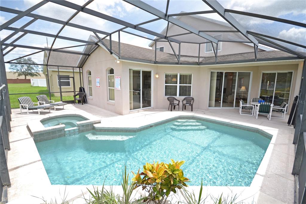 A screened-in patio features a swimming pool, a hot tub, and outdoor furniture — 423 CORVINA DRIVE, DAVENPORT, FL