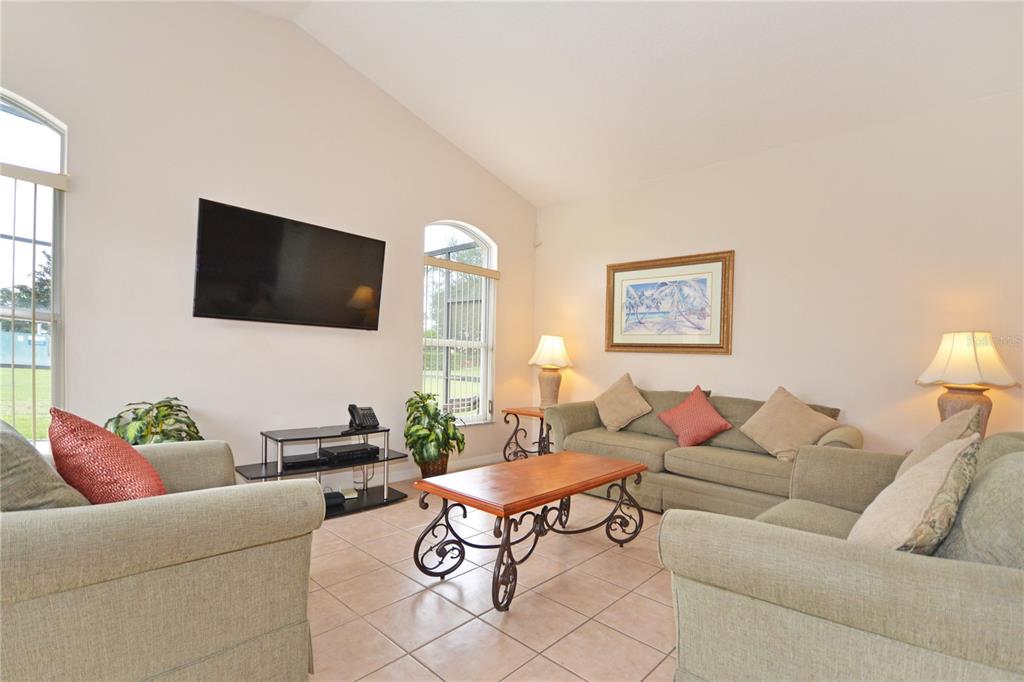 A living room features light tile floors, a vaulted ceiling, and beige upholstered furniture — 423 CORVINA DRIVE, DAVENPORT, FL