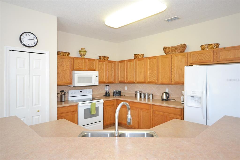A kitchen features light wood cabinets, white appliances, a double sink, and a breakfast bar — 423 CORVINA DRIVE, DAVENPORT, FL