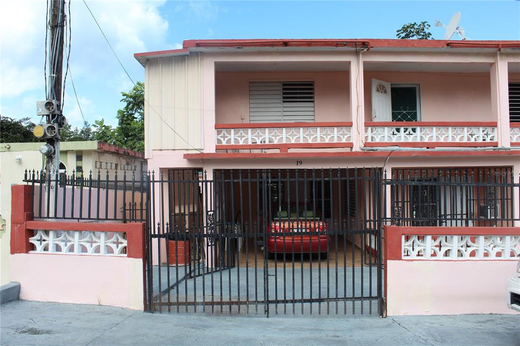 A two-story pink residential building features a gated ground-level carport and an upper balcony — 19 CALLE CORAL, VIEQUES, PR