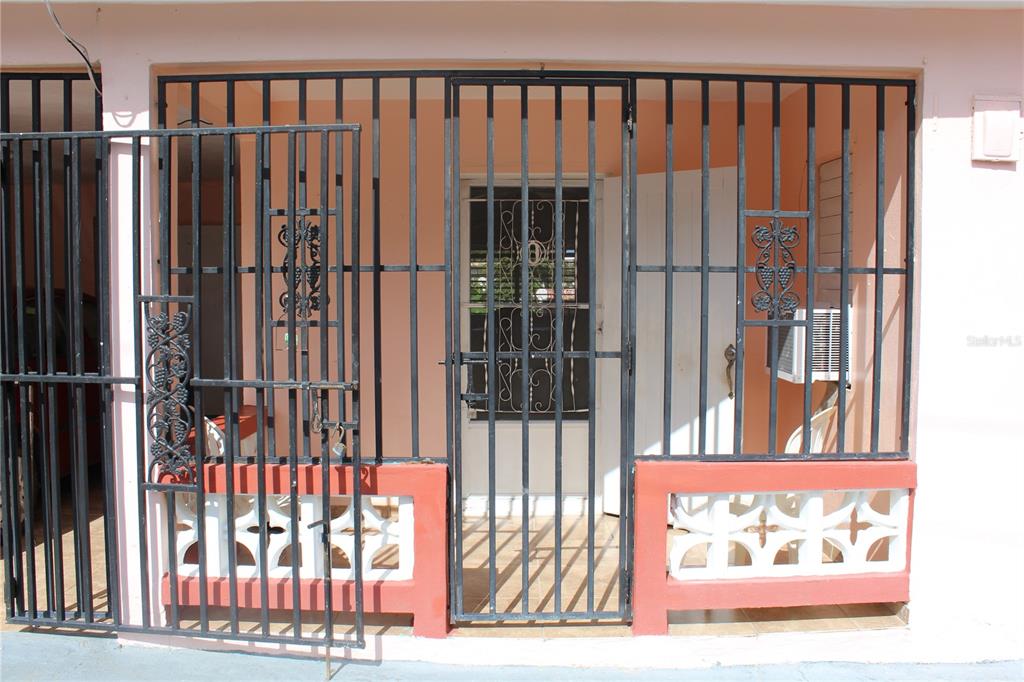 A covered porch features a black metal security gate, decorative ironwork, and a concrete base — 19 CALLE CORAL, VIEQUES, PR