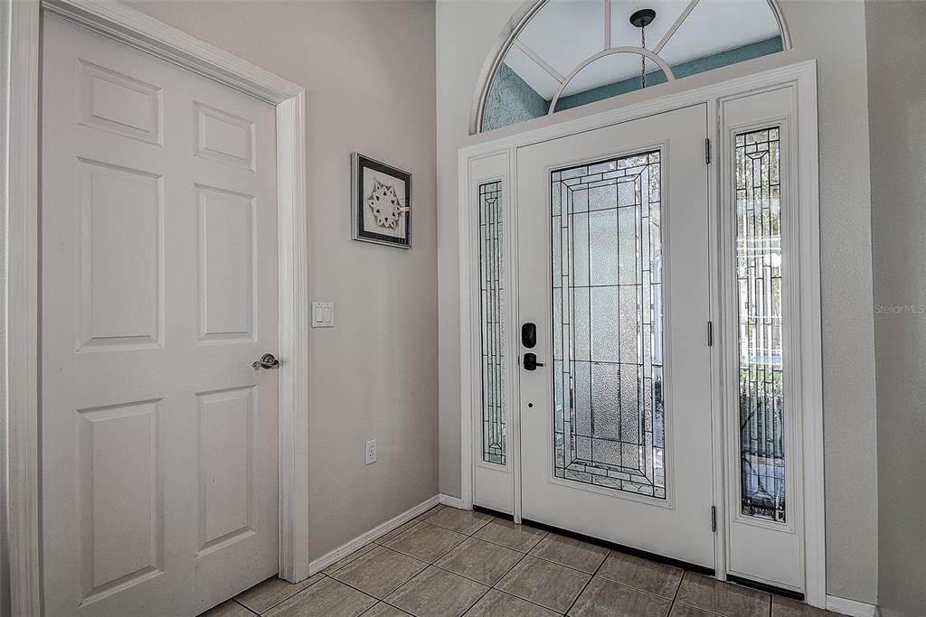 An entryway features a tiled floor, a white door with glass panels, and a side door — 1105 CLIPPERS WAY, TARPON SPRINGS, FL