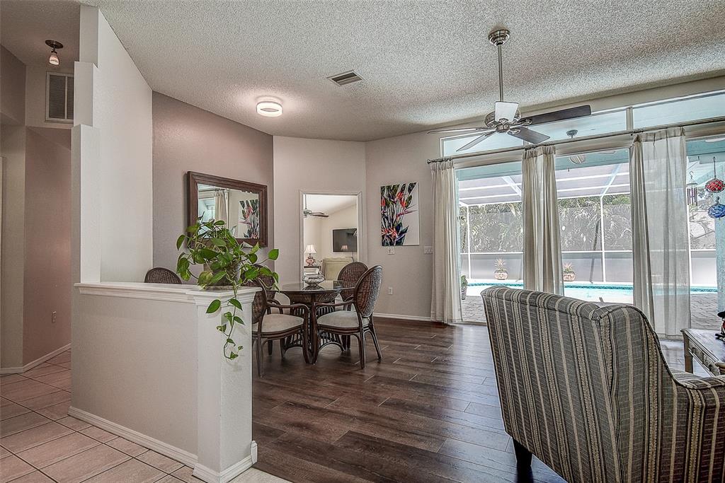 A dining area with a glass table and chairs overlooks a pool through sliding doors — 1105 CLIPPERS WAY, TARPON SPRINGS, FL