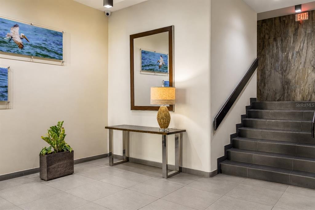 A modern lobby features a console table, a mirror, wall art, and a tiled staircase — 864 ASHFORD AVE. UNIT 712, SAN JUAN, PR