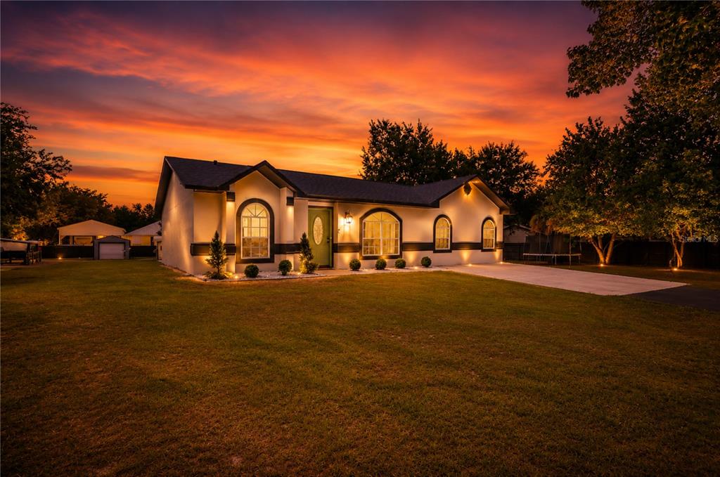 A backyard patio features a covered seating area, a stone fire pit, and string lights — 3346 TARRAGON STREET, COCOA, FL