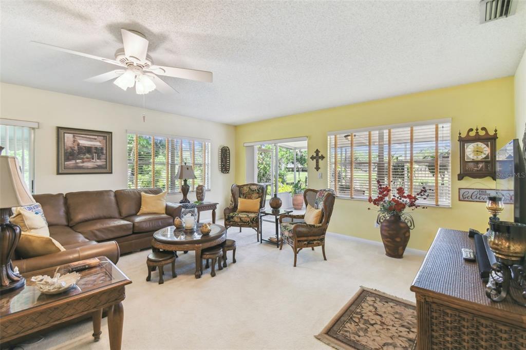 A living room features a brown leather sectional, two patterned armchairs, and a ceiling fan — 441 SAN JOSE DRIVE, WINTER HAVEN, FL