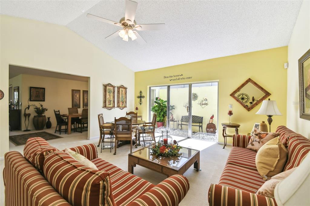 A living room with striped sofas, a glass coffee table, and a sliding door to a patio — 441 SAN JOSE DRIVE, WINTER HAVEN, FL