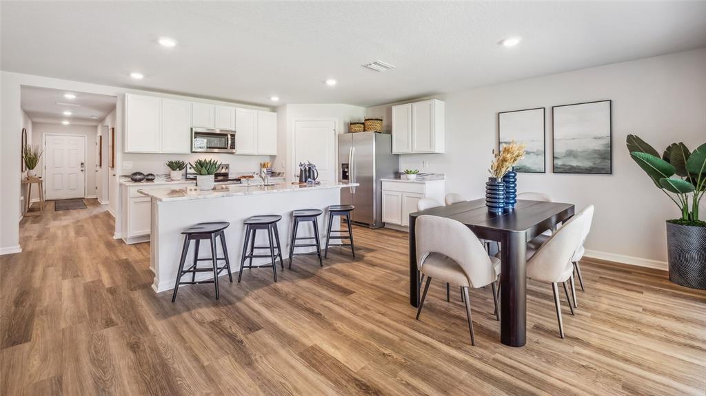 A bright kitchen and dining area features white cabinetry, a wooden table, and light flooring — 5731 SILVER MOONLIGHT DRIVE, PALMETTO, FL