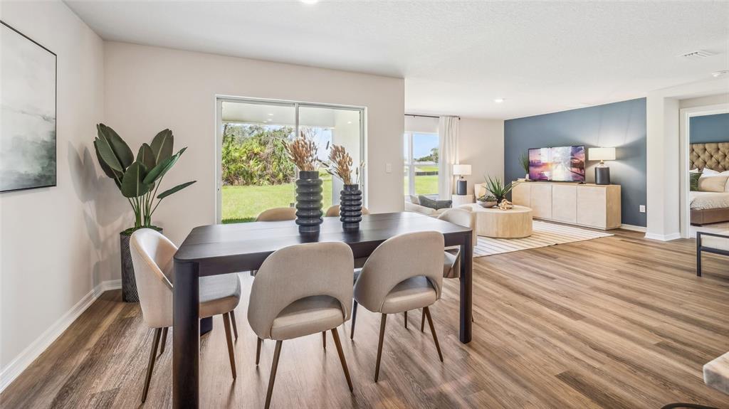 A bright living and dining area features light wood flooring, blue curtains, and neutral furniture — 5731 SILVER MOONLIGHT DRIVE, PALMETTO, FL