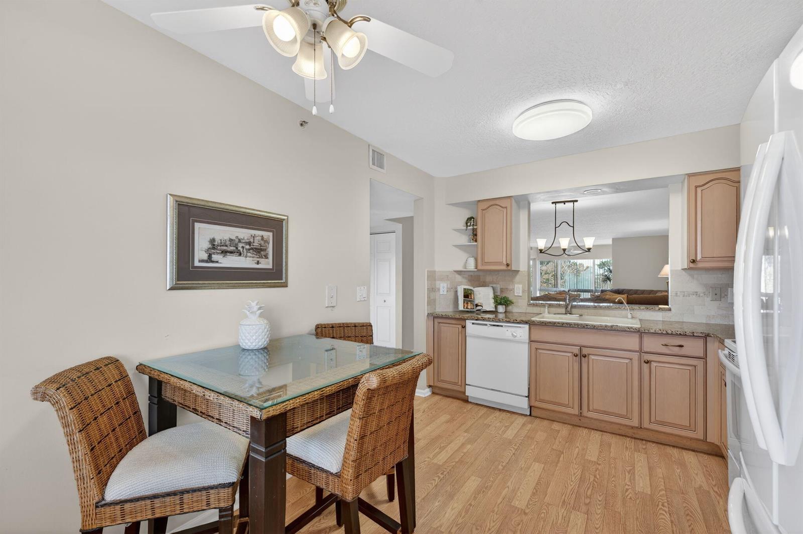 A dining room features a wooden table with six chairs, a chandelier, and tile flooring — 5906 Crystal Shores Drive # 404, Boynton Beach FL 33437, BOYNTON BEACH, FL