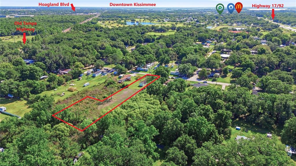 An aerial view shows a rectangular plot of land outlined in red amidst wooded surroundings — 1604 VINTAGE STREET, KISSIMMEE, FL