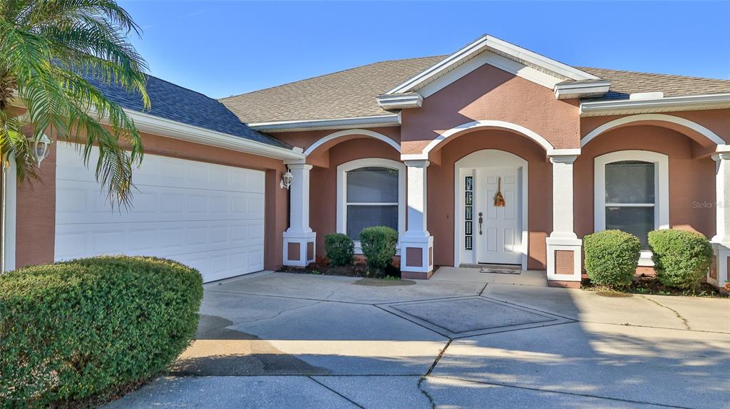 A single-story house with a white garage door, arched entryway, and a concrete driveway — 552 CARO COURT, NEW SMYRNA BEACH, FL