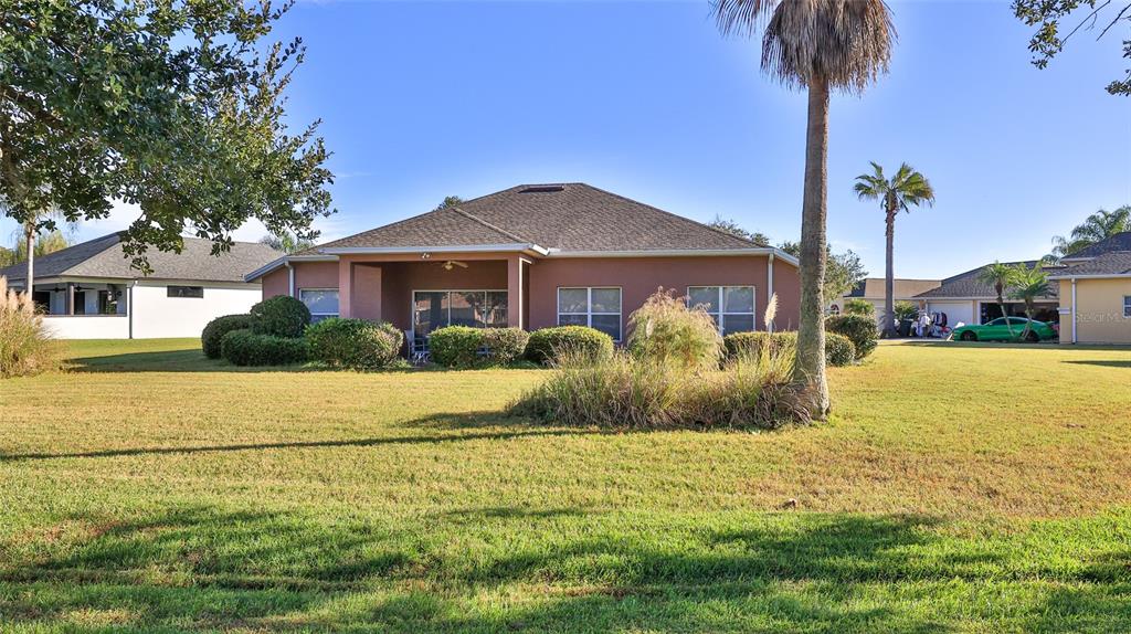 A single-story house with a tan stucco exterior and a large grassy backyard — 552 CARO COURT, NEW SMYRNA BEACH, FL