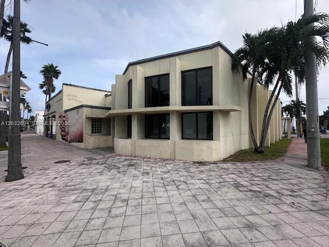 A beige two-story commercial building with large windows stands next to a paved walkway — 1250 Normandy DR, Miami Beach FL 33141, MIAMI BEACH, FL