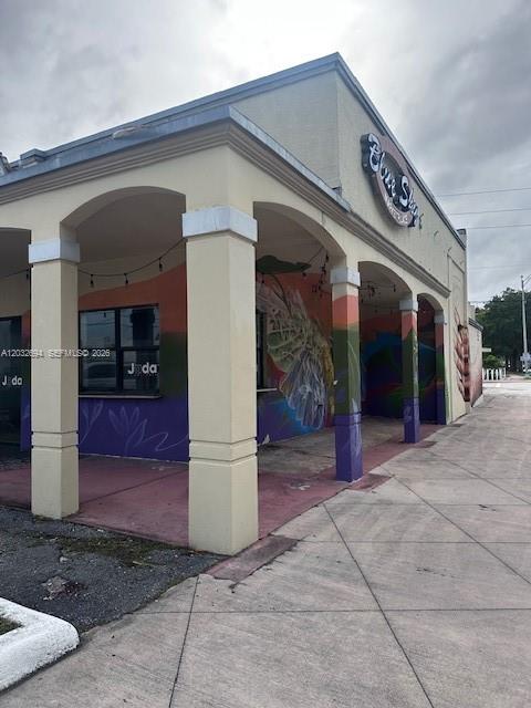 An exterior view of a commercial building with a covered walkway and colorful wall murals — 1250 Normandy DR, Miami Beach FL 33141, MIAMI BEACH, FL