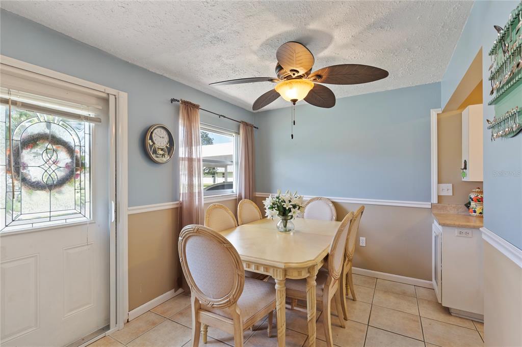 A dining room features a light-colored table, six chairs, a ceiling fan, and tile flooring — 11730 CARISSA LANE UNIT 0, NEW PORT RICHEY, FL