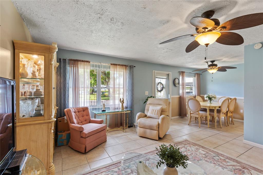 A living and dining area features tile floors, ceiling fans, and a light blue wall — 11730 CARISSA LANE UNIT 0, NEW PORT RICHEY, FL