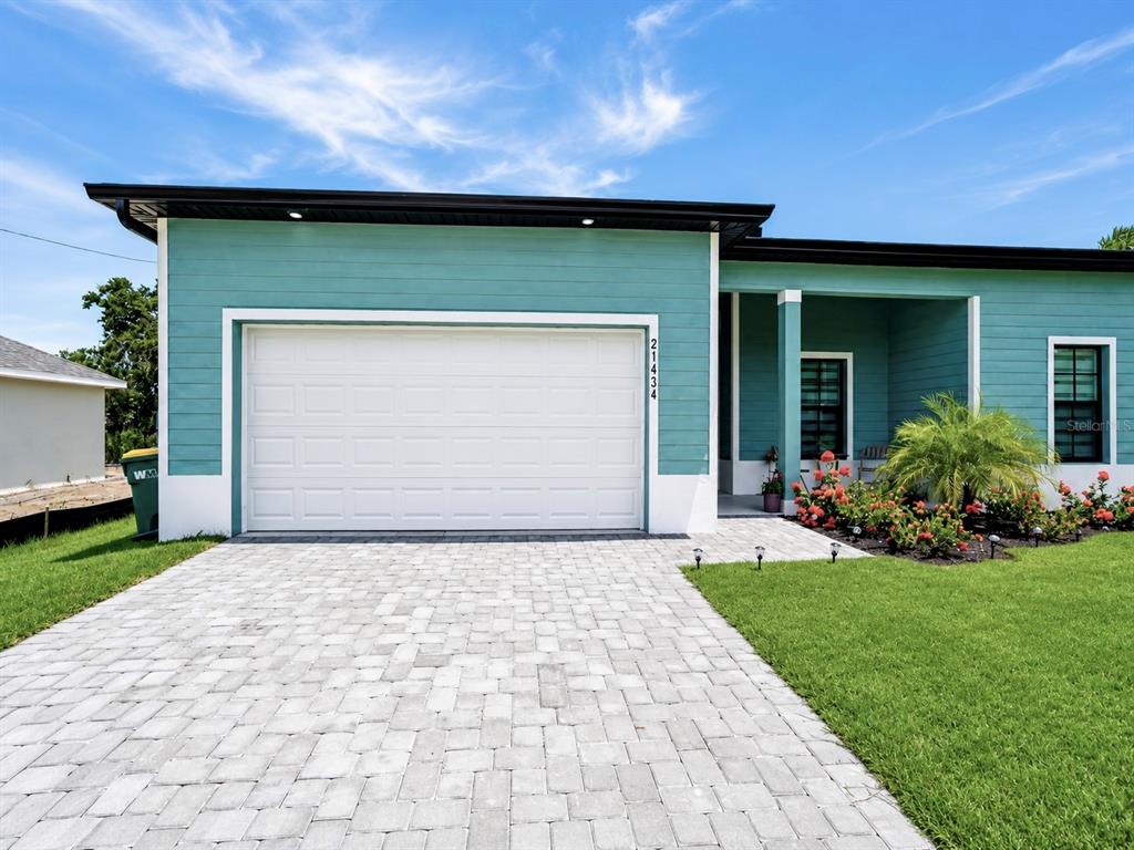 A teal house with a white garage door and a paved driveway under a blue sky — 21434 DEKALS AVENUE, PORT CHARLOTTE, FL