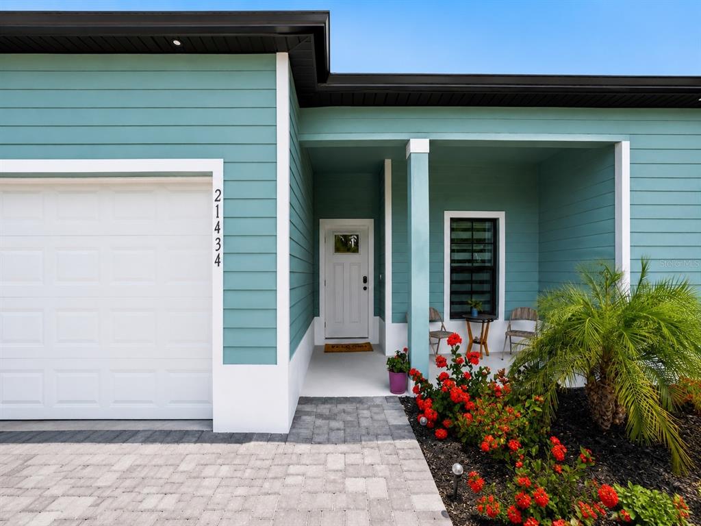 A teal house exterior features a white garage door, a front porch, and red flowers — 21434 DEKALS AVENUE, PORT CHARLOTTE, FL