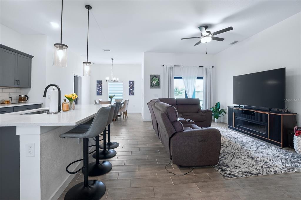 An open-concept kitchen and living area features gray cabinetry, a breakfast bar, and tile flooring — 21434 DEKALS AVENUE, PORT CHARLOTTE, FL