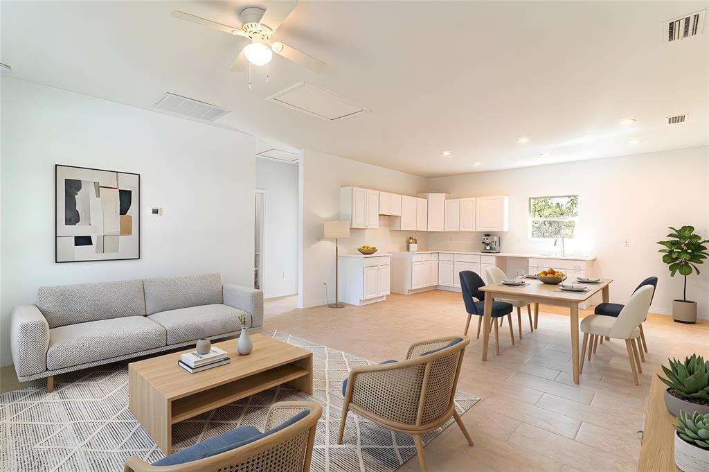 An open-concept living and dining area features white cabinetry, light tile flooring, and modern furniture — 1417 BITTERSWEET STREET, LAKE PLACID, FL