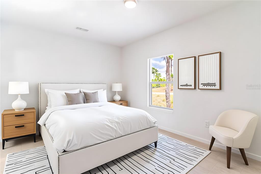 A bedroom features a white bed, two nightstands, a window, and a cream-colored accent chair — 1417 BITTERSWEET STREET, LAKE PLACID, FL