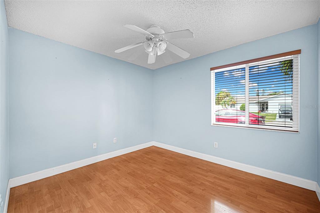 An empty bedroom with light blue walls, wood-look flooring, a ceiling fan, and a window — 26543 SW 122ND PLACE, HOMESTEAD, FL