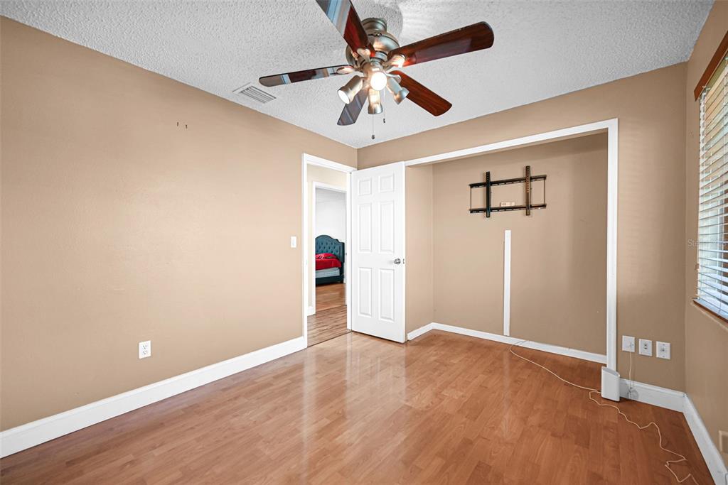 A bedroom with tan walls, wood-look flooring, a ceiling fan, and an open closet — 26543 SW 122ND PLACE, HOMESTEAD, FL