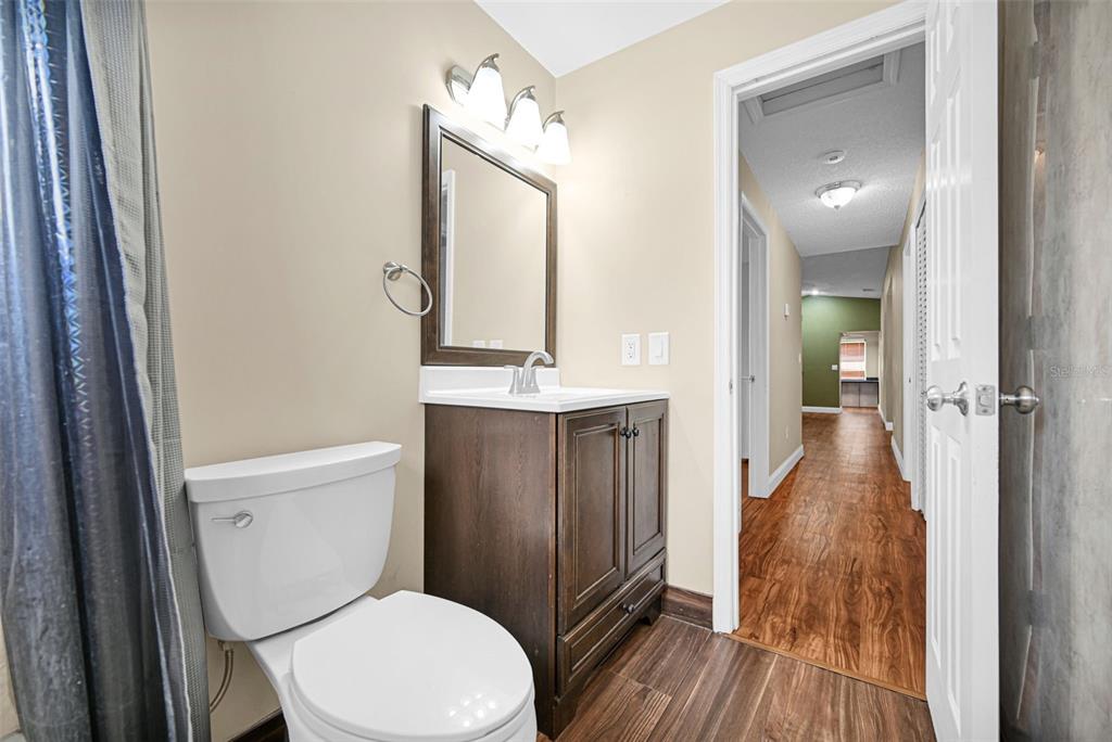 A bathroom features a dark wood vanity, a white toilet, and a doorway to a hallway — 26543 SW 122ND PLACE, HOMESTEAD, FL