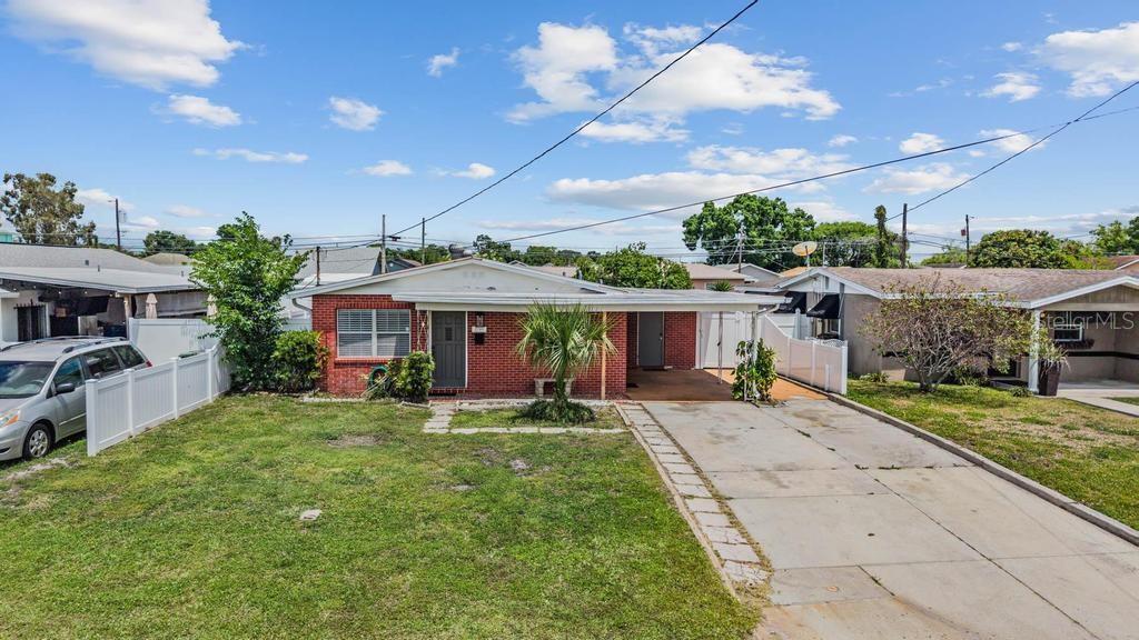 A single-story brick house features a front carport, a concrete driveway, and a grassy lawn — 2709 W ABDELLA STREET, TAMPA, FL