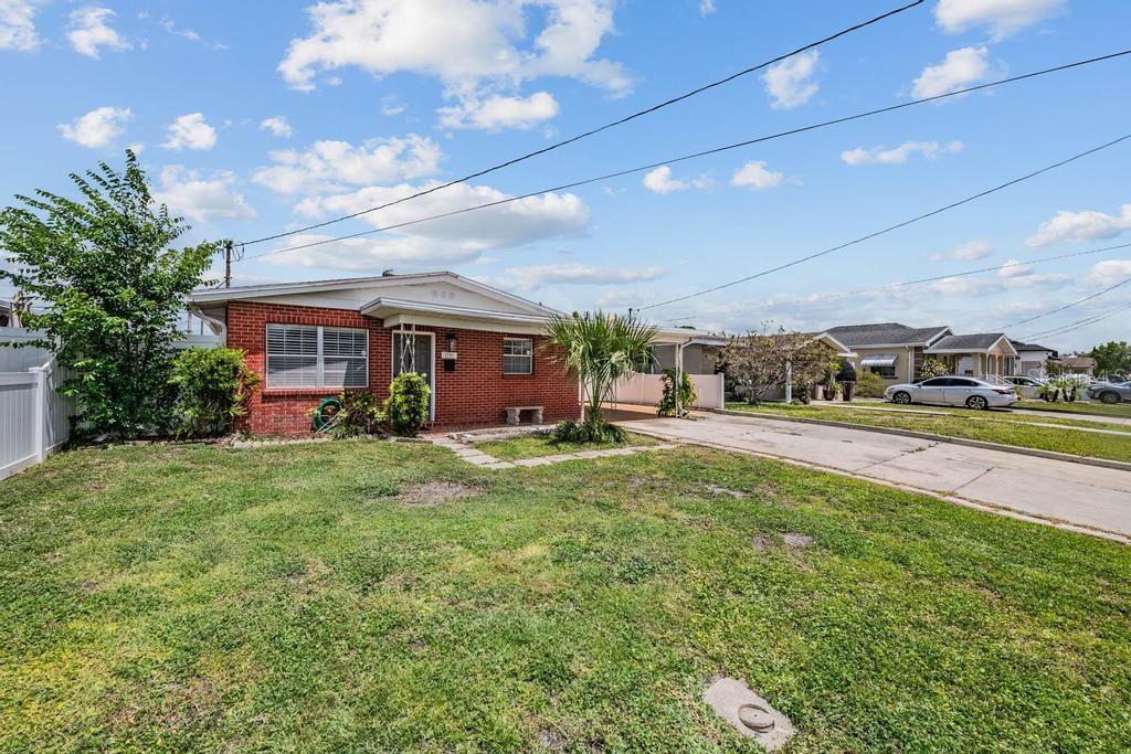 A single-story brick house with a front lawn and a concrete driveway under a sky — 2709 W ABDELLA STREET, TAMPA, FL