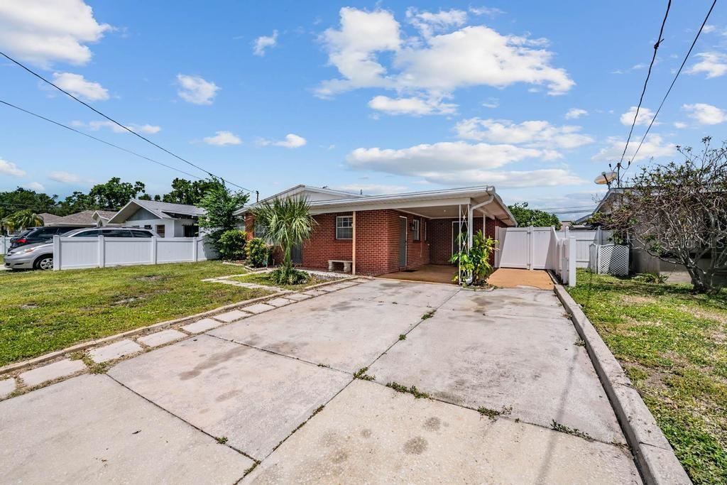 A brick house with a concrete driveway and a covered carport under a blue sky — 2709 W ABDELLA STREET, TAMPA, FL